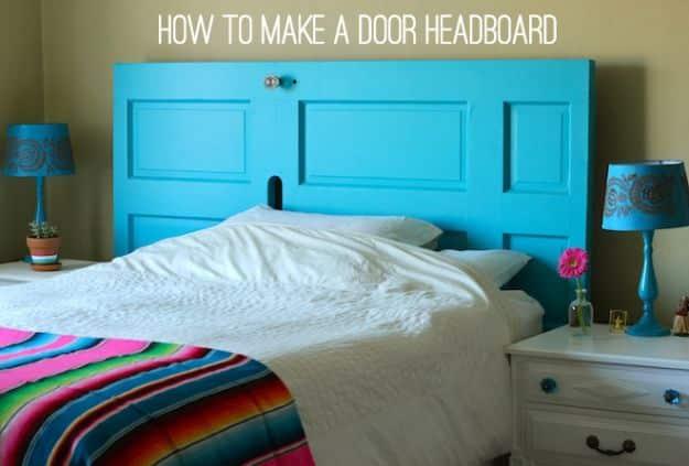 Turquoise painted paneled door mounted sideways as a headboard behind a bed with blue lamps either side