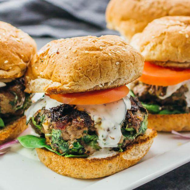 Greek burgers stuffed with spinach, feta and sun dried tomatoes on toasted buns with tzatziki sauce on top