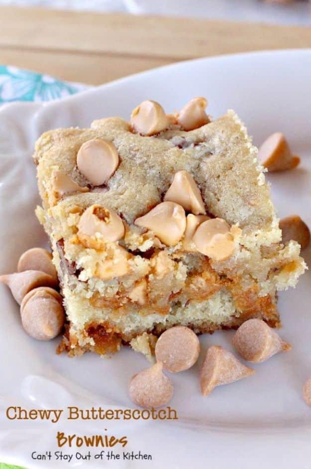 Chewy butterscotch brownies on a white plate with butterscotch chips scattered beside a thick golden square
