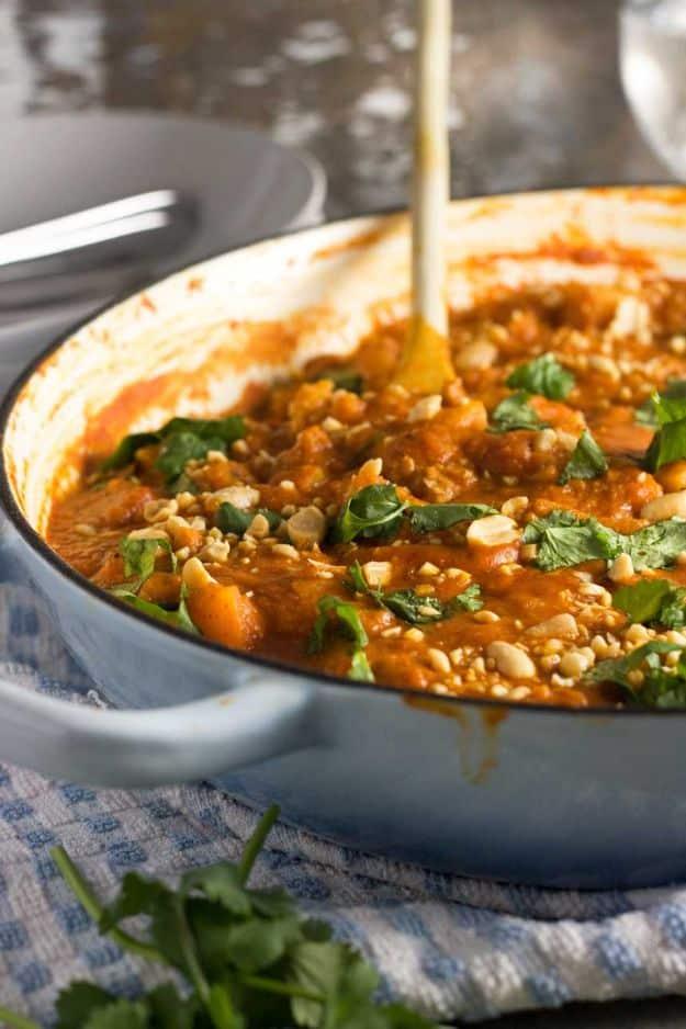 Chicken and butternut squash satay curry in a large pan with spinach, peanuts and fresh coriander on top