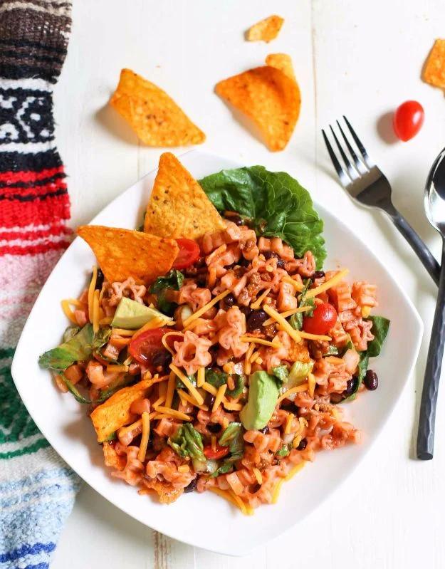 Mexican chef pasta salad with Doritos, taco beef, black beans, tomatoes and avocado on a white plate
