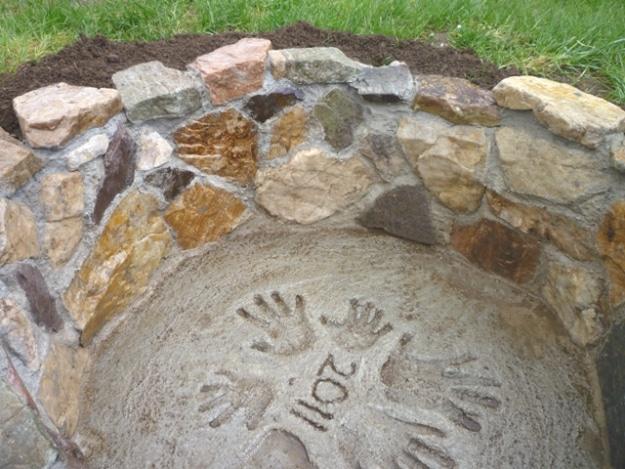 Personalized firepit base in poured concrete with children's handprints and the year 2011 pressed into it
