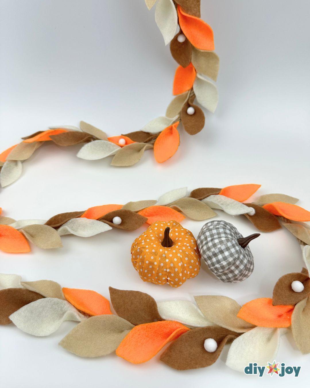DIY felt leaf garland made with colorful felt leaves, rope, and pom-poms for a Thanksgiving display.
