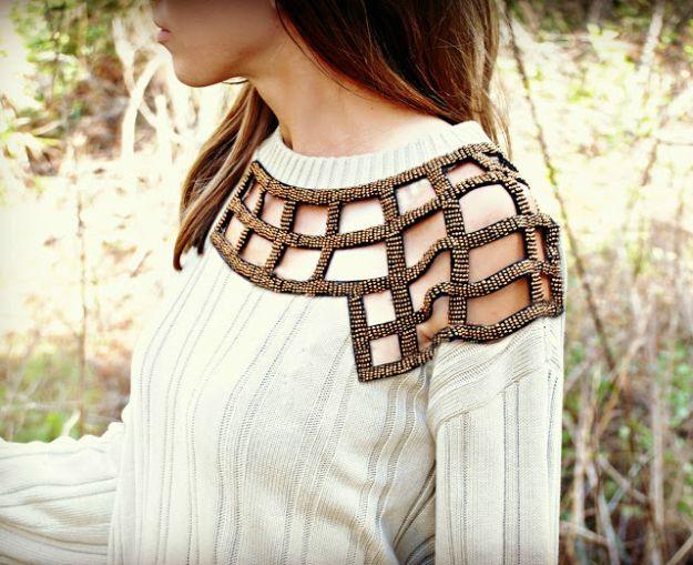 Cream cable knit sweater with a beaded geometric cutout applique across one shoulder and the upper chest