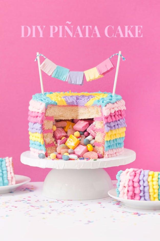 Pastel striped pinata birthday cake cut open with colorful candy spilling out onto a white cake stand