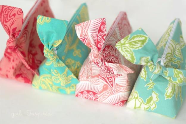 A row of flat lined zipper pouches in mixed cotton prints with colorful zippers, batched and ready for a craft fair table