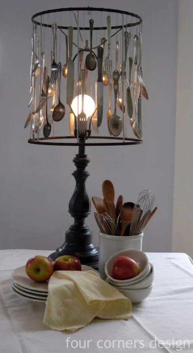 Lamp with a bare wire shade frame hung with forty spoons, forks and knives around a lit bulb on a table