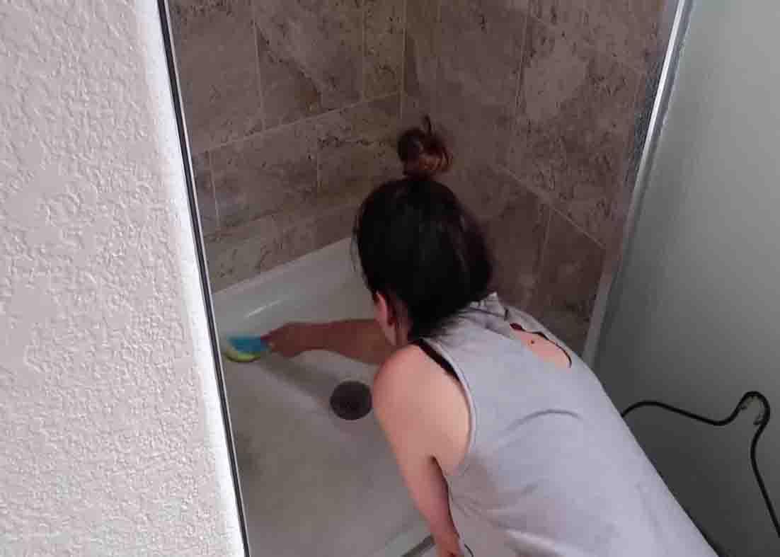 Scrubbing the shower with the DIY cleaning solution