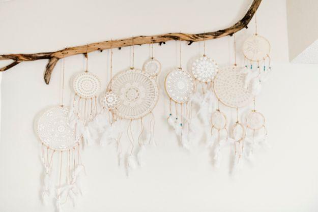 Row of cream lace doily dreamcatchers set in wooden hoops, hanging from a driftwood branch on a white wall