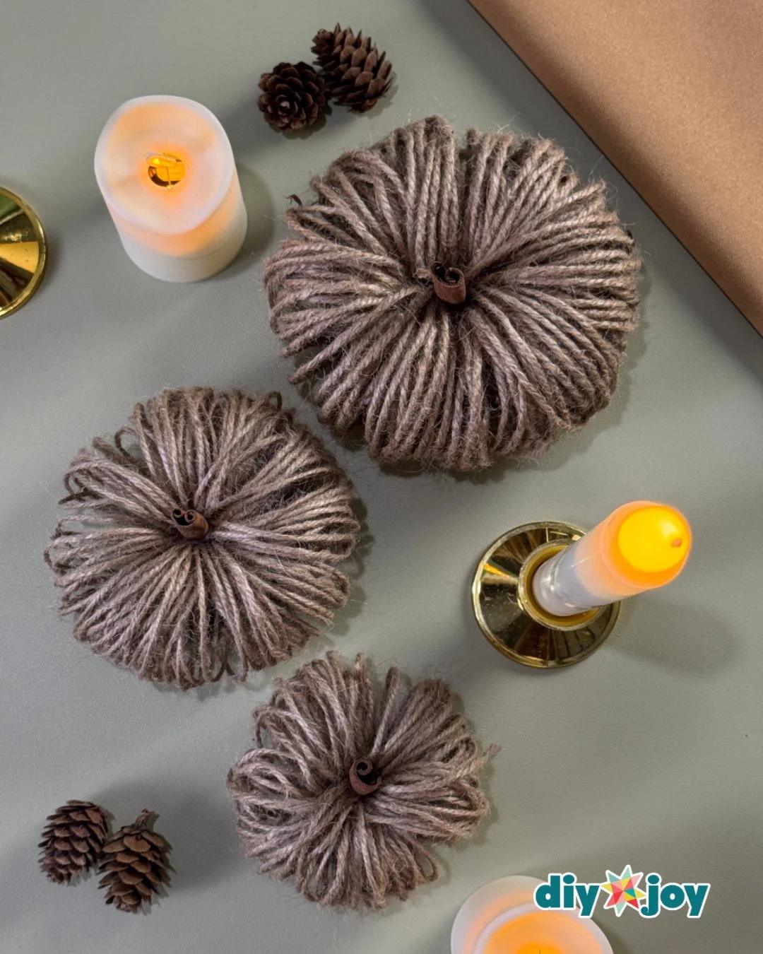 Twine pumpkin fall craft displayed with candles as rustic Thanksgiving table decor made from a toilet paper roll.