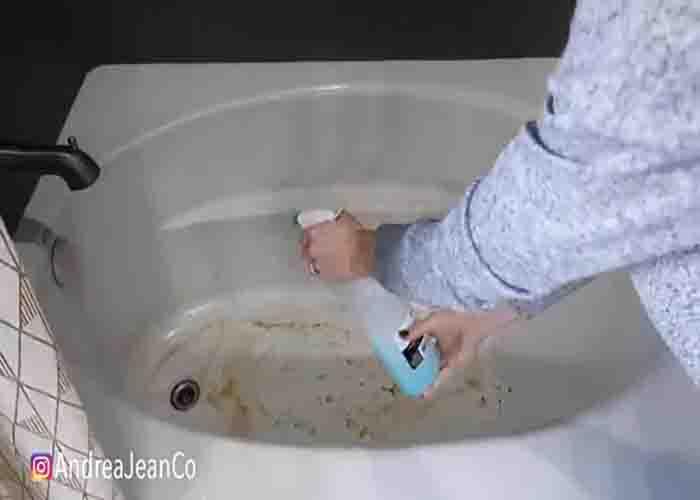 Spraying the miracle shower cleaner to the bathtub