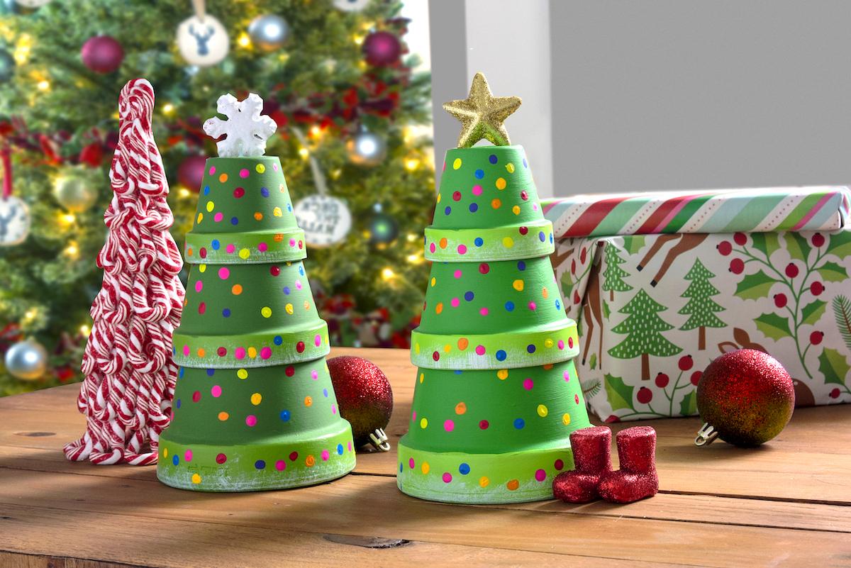 Two stacked clay pot Christmas trees painted green with rainbow dot lights, one topped with a snowflake and one with a star