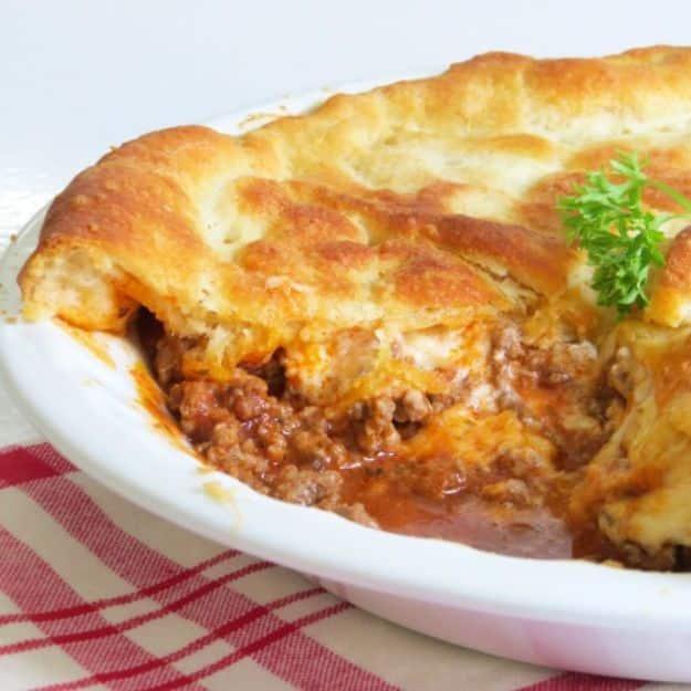 Ground beef pie in a deep pie dish with a golden crescent roll crust brushed with butter and parmesan