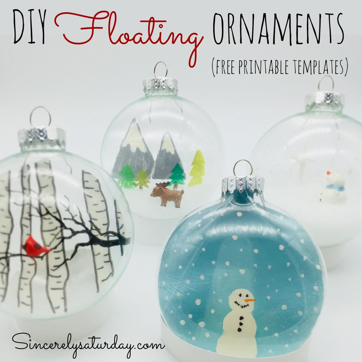 Four clear floating ornaments with painted scenes inside: birch trees with a cardinal, mountains with a deer and a snowman