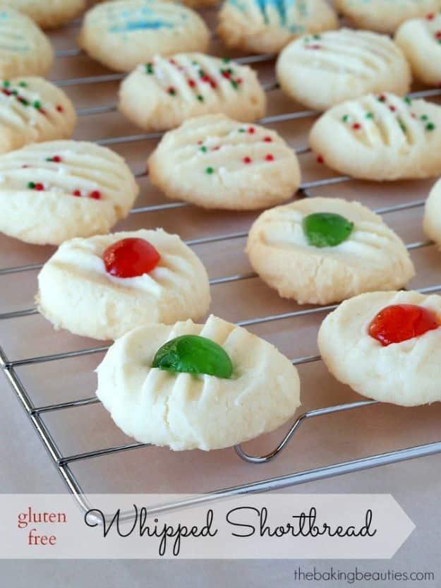 Gluten free whipped shortbread cookies topped with candied cherries and colored sprinkles on a baking tray