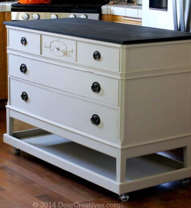 Cream painted dresser on casters with a dark top and ring pulls, rebuilt into a rolling kitchen island