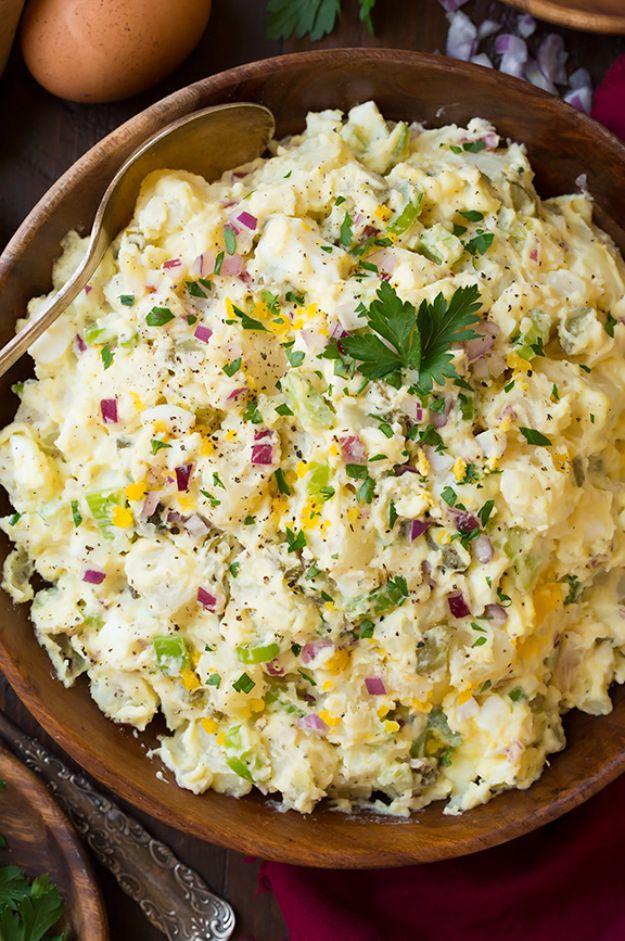Classic creamy potato salad in a wooden bowl flecked with parsley, egg and red onion with brown eggs behind