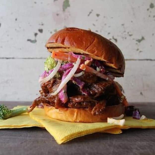 A barbecue brisket sandwich stacked with red cabbage slaw and onion on a brioche bun, a celebrity chef lunch