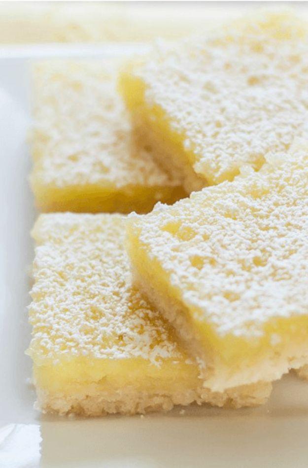 Gluten free lemon bars dusted with powdered sugar on a shortbread crust, cut into small neat squares on a board