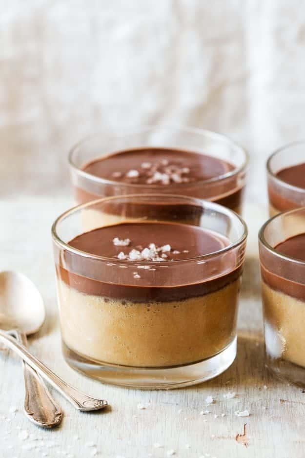 Vegan peanut butter mousse in small glasses topped with dark chocolate ganache and flaky sea salt flakes