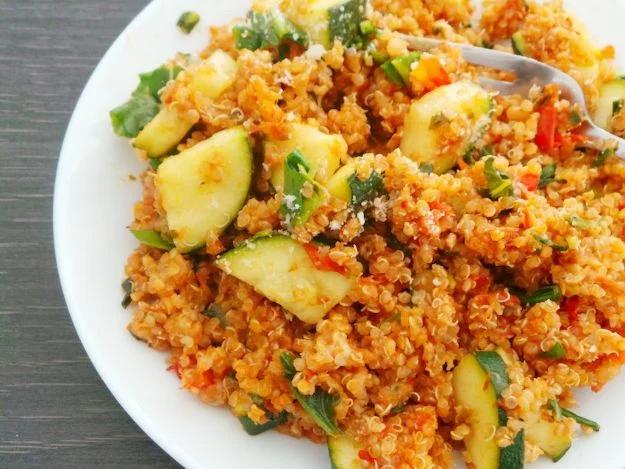Tomato basil quinoa risotto served creamy in a shallow bowl with fresh basil leaves scattered over the top