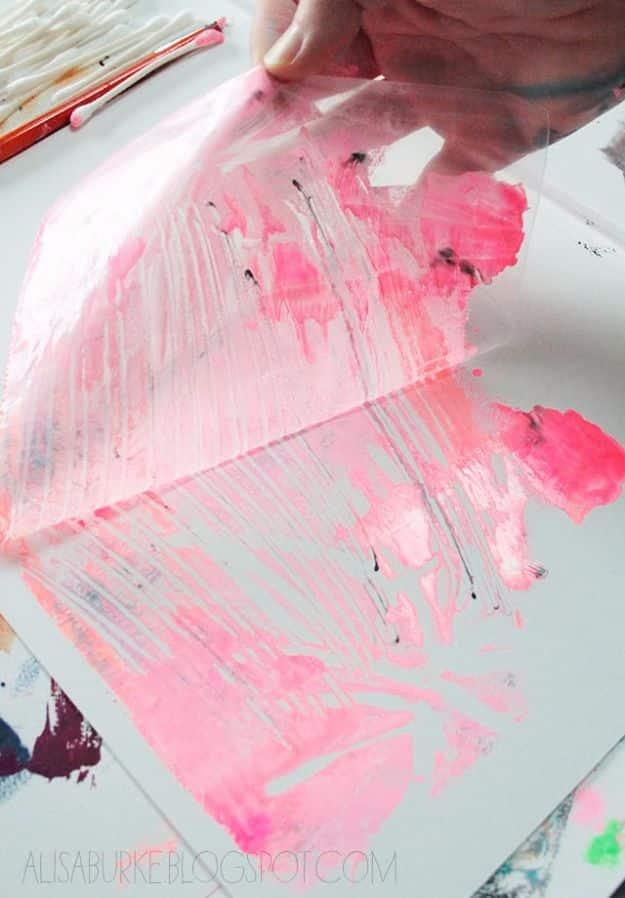 A hand peeling a plastic bag away from paper to reveal a pink and black printed mark, with cotton swabs nearby