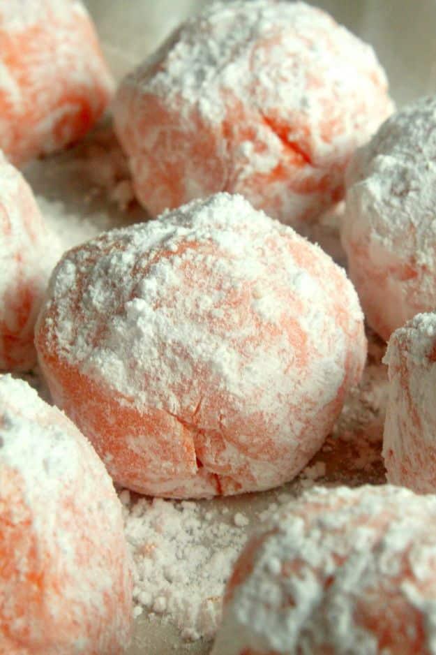No bake orange creamsicle truffles rolled in powdered sugar on a tray, an easy no bake dessert idea, an easy no bake dessert