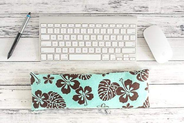 A long padded keyboard wrist rest in printed cotton lying in front of a keyboard on a desk beside a mouse