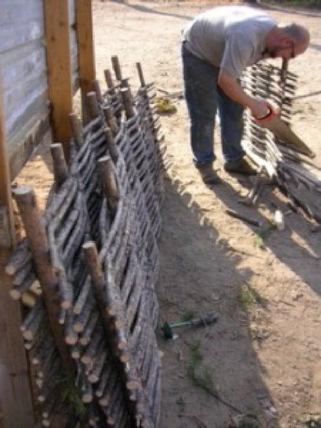 Pine wattle fencing, a dense woven fence of pine branches between upright stakes with a person weaving a branch into place