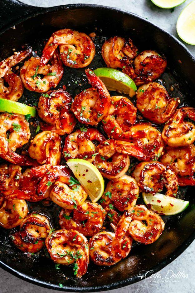 Browned butter honey lime shrimp in a dark cast iron skillet with fresh lime wedges and chopped parsley
