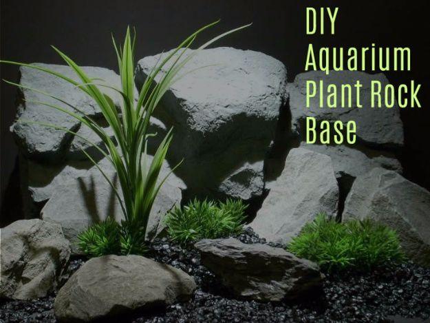 DIY aquarium plant rock base with a spiky green plant set into grey stones among slate rocks in a tank