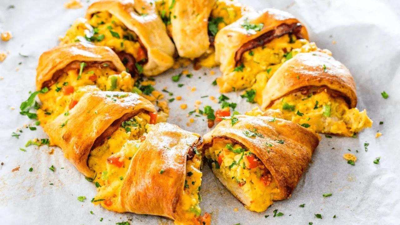 Crescent bacon breakfast ring filled with scrambled eggs, bell pepper, bacon and cheddar on a sheet pan