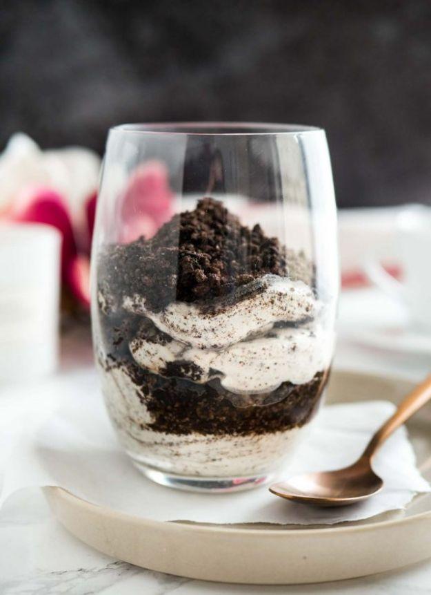 No bake Oreo cheesecake parfaits layered in glasses with cookie crumbs and a creamy cheesecake filling