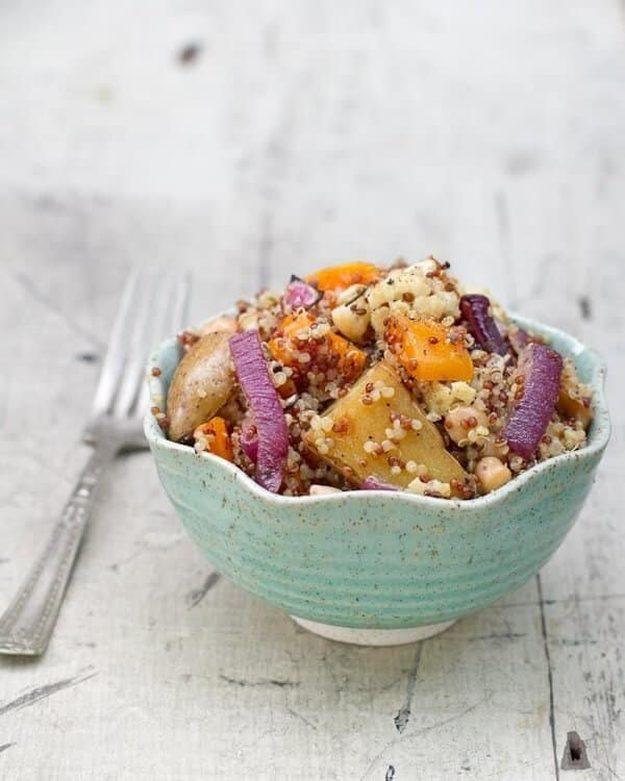 Quinoa with roasted fingerling potatoes, squash, cauliflower and chickpeas in a turquoise scalloped bowl, white wood