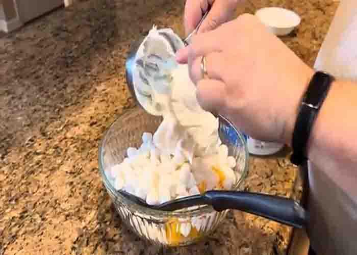 Adding the cool whip to the five cup salad