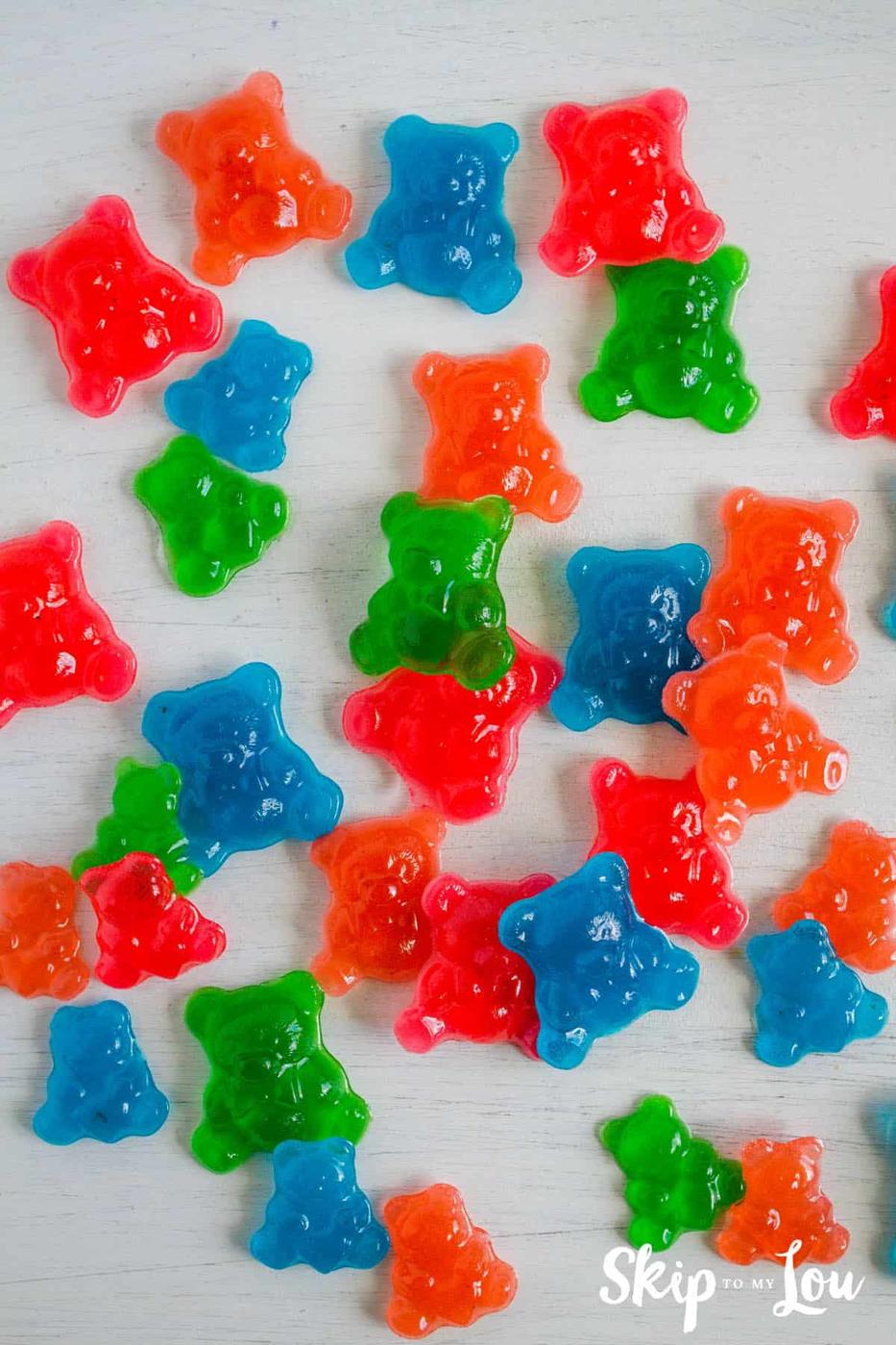 Fall craft for kids, homemade gummy bear candies in red, green, orange and blue scattered across a white surface