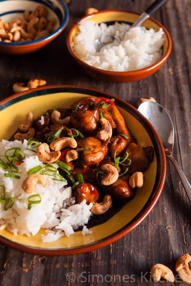 Coca Cola chicken with cashew nuts in a bright glazed bowl with scallions beside a bowl of white rice