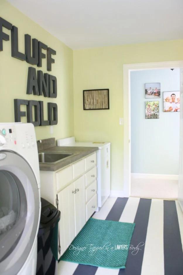 Laundry room with a navy and cream striped painted floor, pale green walls and a white front load washer