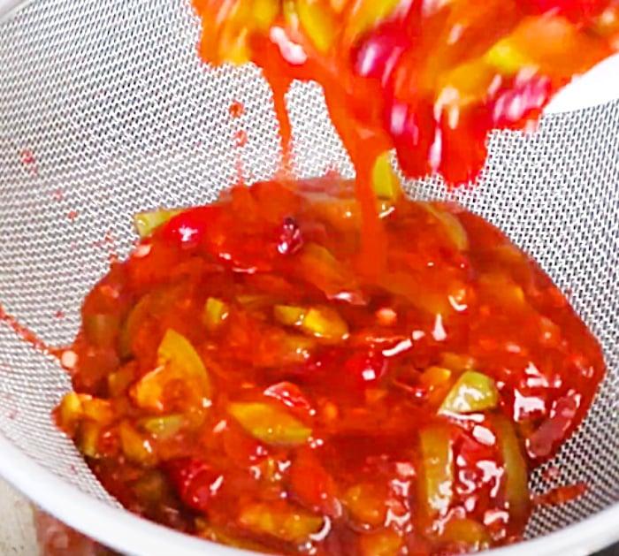 Strain Cooked Cranberries And Jalapenos To Make Jelly