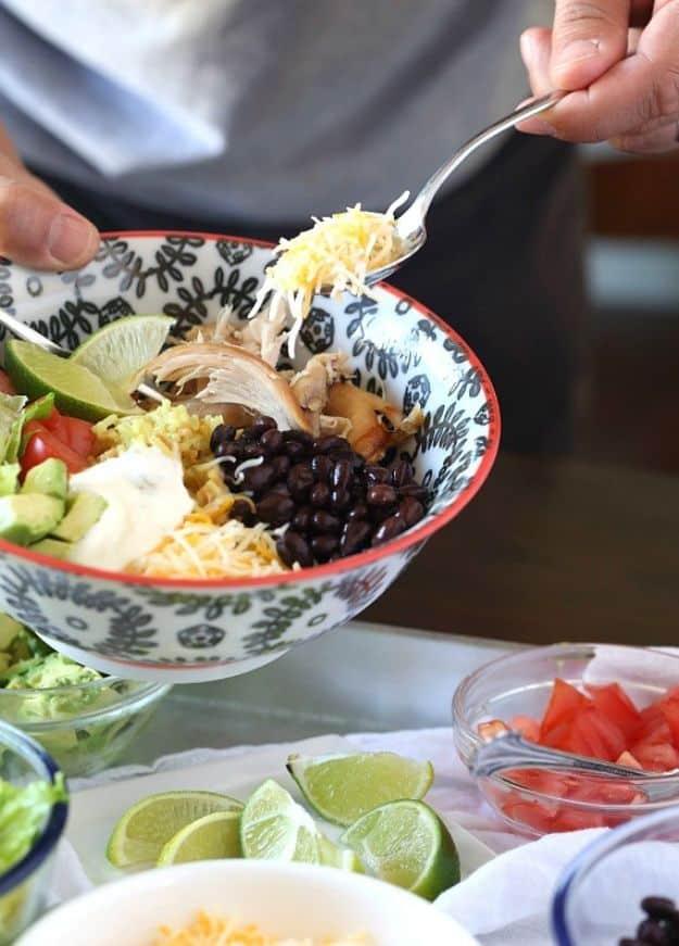 Easy burrito bowls built over rice with shredded chicken, beans, corn and toppings set out in bowls on a busy weeknight