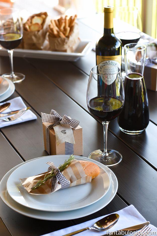 Rustic wine dinner table with a bottle and poured glass, white plates, bread basket and small favor boxes