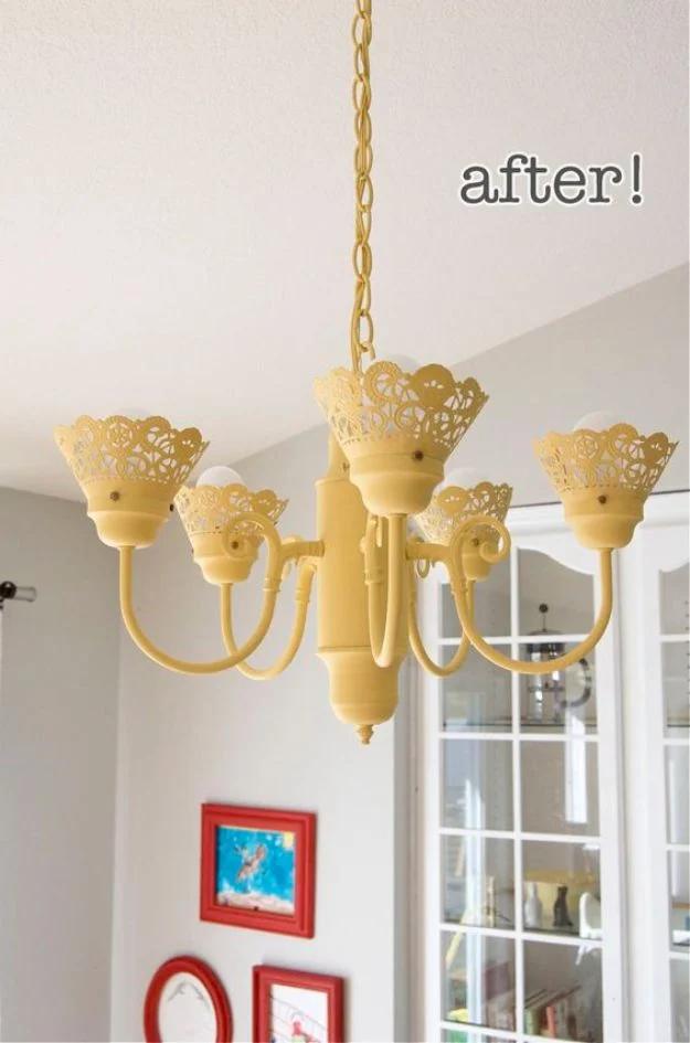 Yellow painted chandelier makeover with foil doily collars around each bulb base, hanging in a bright white room