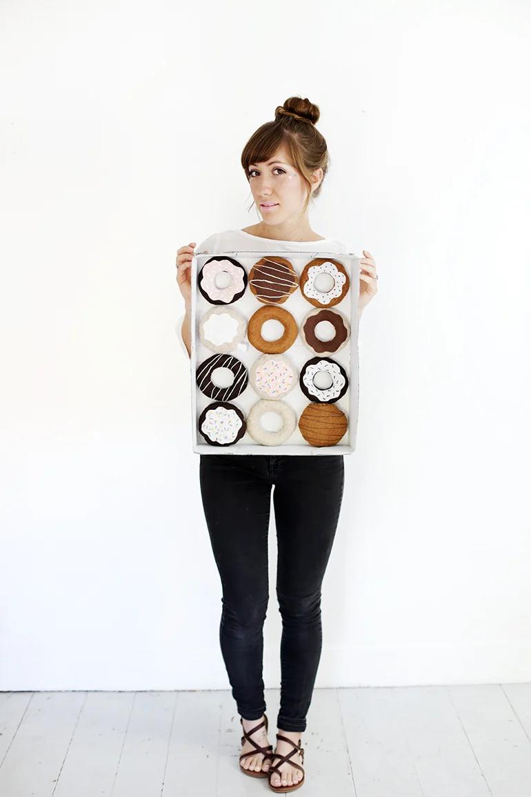 Adult wearing a DIY donut costume with twelve felt donuts arranged inside a painted cardboard bakery box