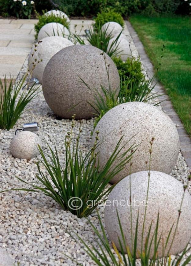 DIY curb appeal concrete garden globes in pale gray set among white gravel and ornamental grasses beside a path
