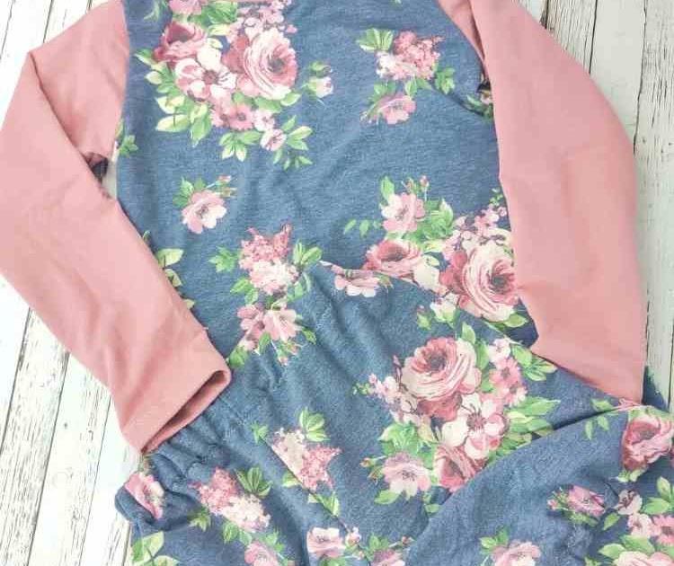 Girls nightgown sewn from navy floral fabric with contrasting dusty pink sleeves laid on weathered wood