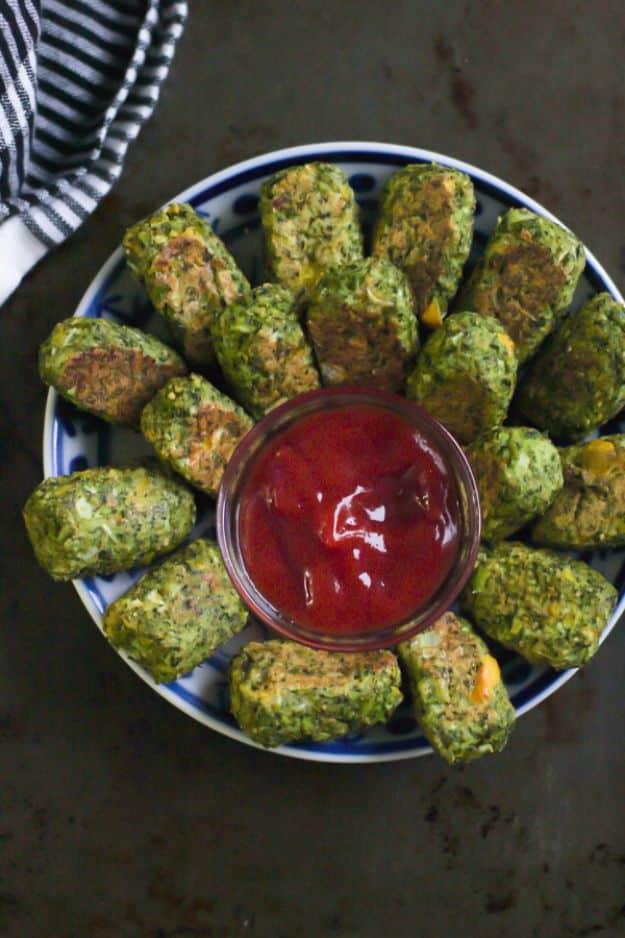 Low carb broccoli tots arranged in a ring on a blue rimmed plate around a small glass bowl of tomato ketchup