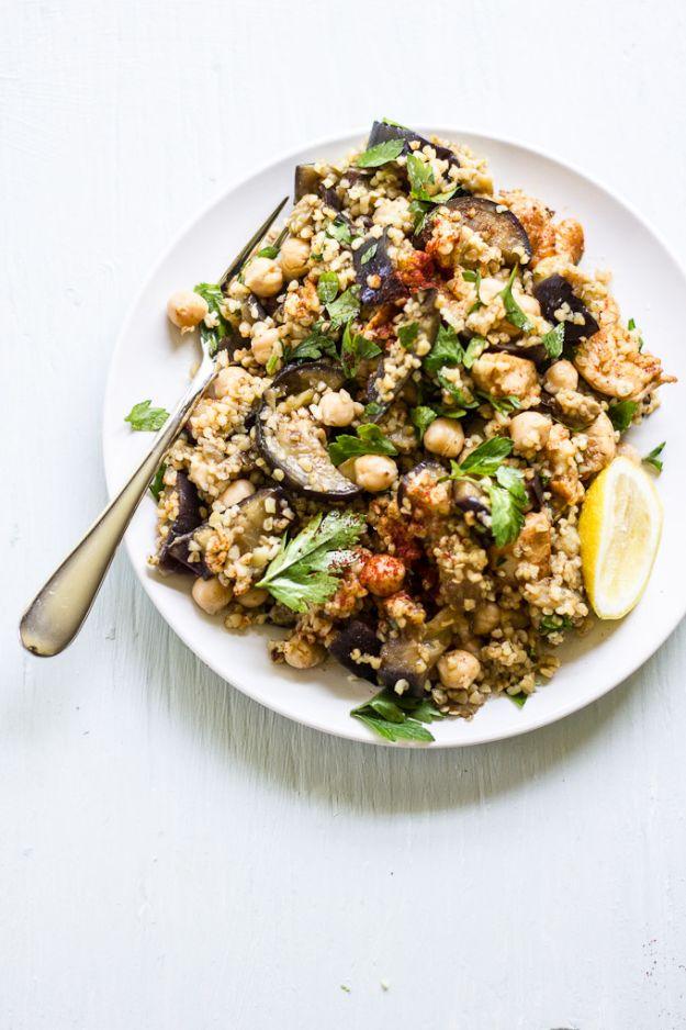 Spiced eggplant chicken and chickpea salad on a white plate with bulgur wheat, parsley and a lemon wedge