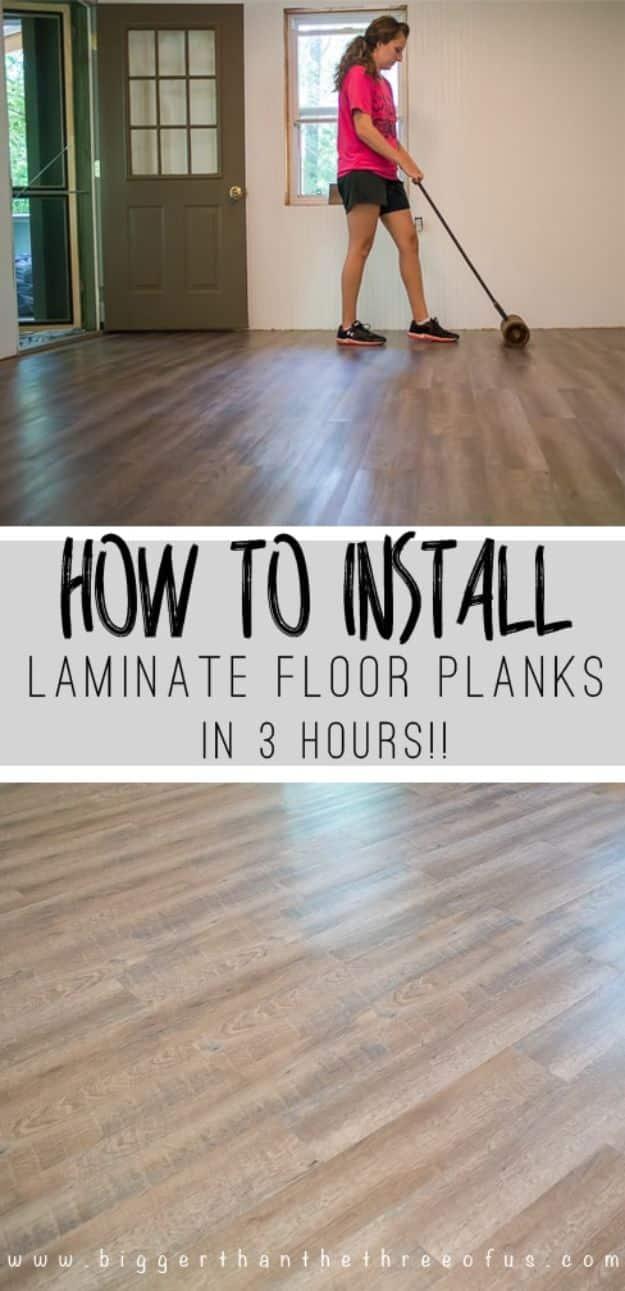 Installing laminate flooring, a dark plank floor being rolled flat with a heavy floor roller in an empty room