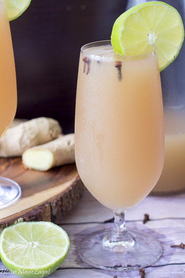 Homemade Caribbean ginger beer, cloudy and pale gold, poured over ice with fresh ginger root nearby beside fresh ginger root