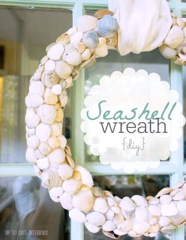 DIY seashell wreath covered edge to edge in pale shells, hanging on a window with a ribbon at the top